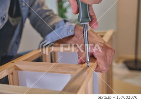 Man assembling wooden furniture using a screwdriver Man assembling wooden furniture using a screwdriver 137002070