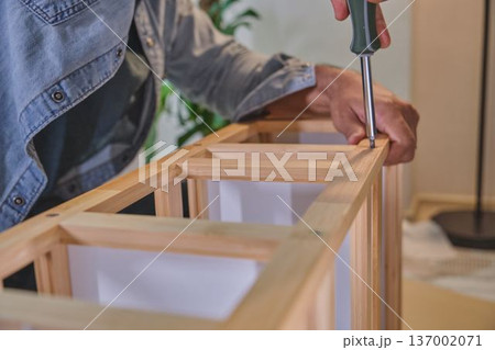 Person assembling wooden furniture with screwdriver at home 137002071