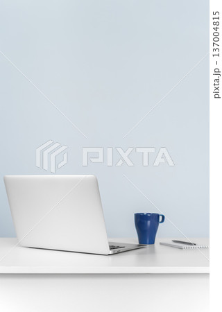 Laptop and coffee mug on white desk against blue wall Laptop and coffee mug on white desk against blue wall 137004815