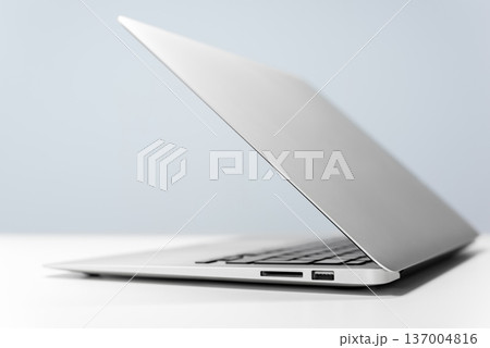 Modern laptop on white desk against blue wall 137004816
