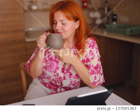 young woman working on tablet at kitchen 137005363