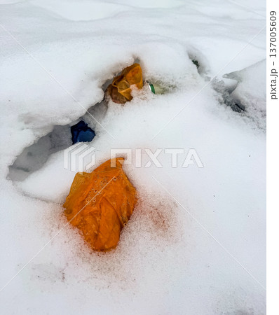 Colorful plastic garbage, bags and bottles, polluting the fresh white snow in winter. Environmental conservation concept. 137005609