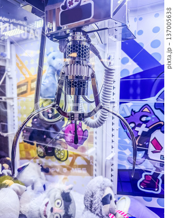 Claw machine arcade game close-up. Metal grabber ready to pick a stuffed animal toy prize from the pile inside the glass box. 137005638