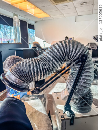 Professional beautician doing a manicure or tattoo for a client in a salon with a fume extractor and a magnifying lamp. 137005639