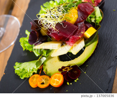 Deliciously salad of raw tuna with avocado, mango and greens at plate Deliciously salad of raw tuna with avocado, mango and greens at plate 137005836