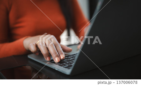 Close up of a woman's hands with orange nails typing on a laptop keyboard. Concept of remote work, professional freelancer, online business communication, and modern digital lifestyle. 137006078