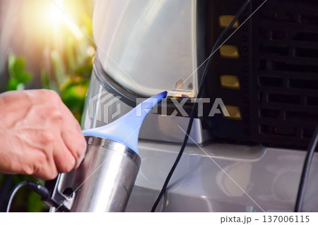 The technician is spraying a coating onto the car's headlights. The technician is spraying a coating onto the car's headlights. 137006115