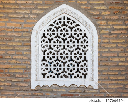 Ornate white jali window set into an exposed brick wall Ornate white jali window set into an exposed brick wall 137006504