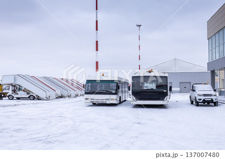 Two airport shuttle buses, empty passenger boarding steps and other equipment on the winter airport Two airport shuttle buses, empty passenger boarding steps and other equipment on the winter airport 137007480