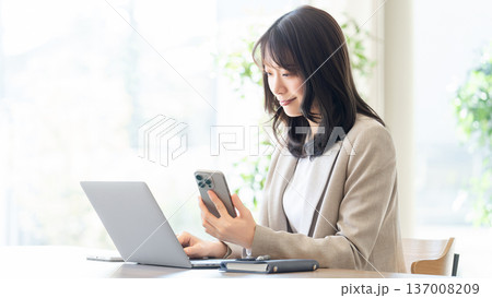 パソコンとスマートフォンを使う女性・ビジネスウーマン パソコンとスマートフォンを使う女性・ビジネスウーマン 137008209