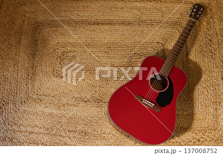 Red Acoustic Guitar on Woven Straw Rug With Warm Natural Texture Red Acoustic Guitar on Woven Straw Rug With Warm Natural Texture 137008752