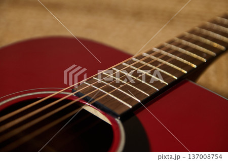 Red Acoustic Guitar Close-Up Showing Fretboard, Strings and Sound Hole With Warm Lighting 137008754
