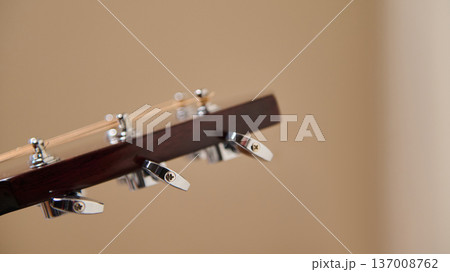 Close-Up Acoustic Guitar Headstock With Chrome Tuning Pegs On Neutral Background Close-Up Acoustic Guitar Headstock With Chrome Tuning Pegs On Neutral Background 137008762