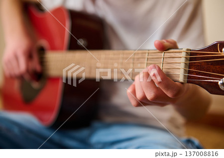 Young Person Playing Acoustic Guitar Close-Up Showing Fingers on Fretboard Young Person Playing Acoustic Guitar Close-Up Showing Fingers on Fretboard 137008816