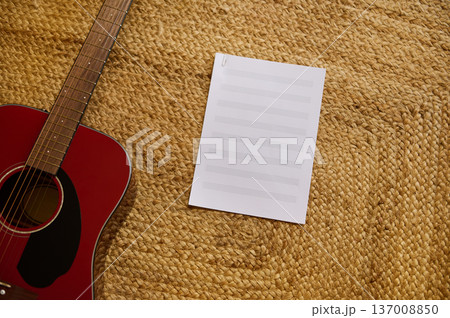 Red Acoustic Guitar With Blank Sheet Music on Woven Straw Rug 137008850
