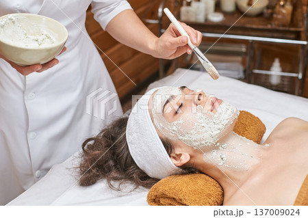 Asian Young Female Receiving Relaxing Facial Treatment At Spa With Rejuvenating Mask Asian Young Female Receiving Relaxing Facial Treatment At Spa With Rejuvenating Mask 137009024