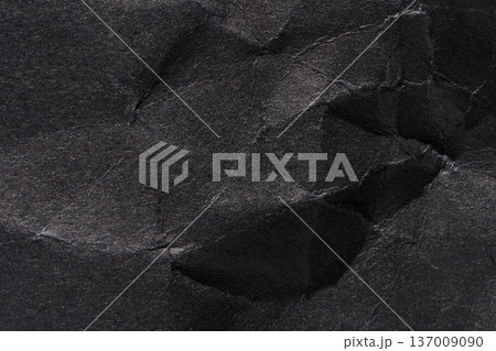 Close-up of crumpled black paper texture with detailed creases and wrinkles Close-up of crumpled black paper texture with detailed creases and wrinkles 137009090
