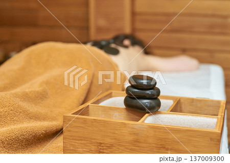 Caucasian Adult Female Relaxing With Hot Stone Massage In Spa Setting For Ultimate Relaxation Caucasian Adult Female Relaxing With Hot Stone Massage In Spa Setting For Ultimate Relaxation 137009300