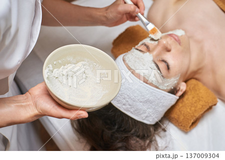 Female Caucasian Young Adult Receiving Facial Treatment With Clay Mask In Spa Setting 137009304