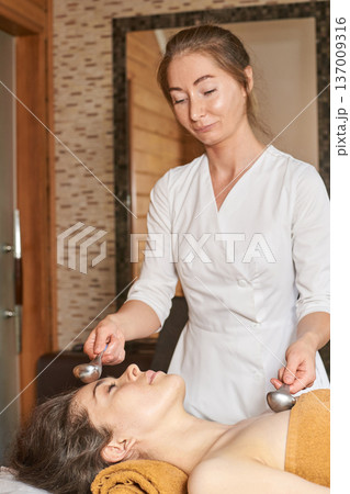 Young Caucasian Woman Receiving Facial Massage From Female Therapist In Spa Setting Young Caucasian Woman Receiving Facial Massage From Female Therapist In Spa Setting 137009316