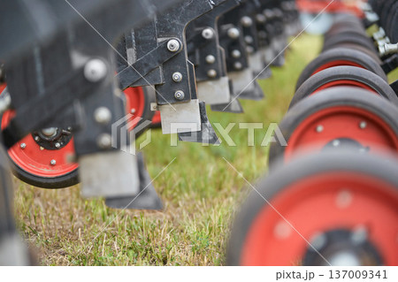 Row of agricultural machinery wheels and metal components on grass field with shallow depth of field 137009341