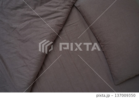 Close-up of elegant grey bedding with textured fabric and neatly arranged pillows for a modern 137009350