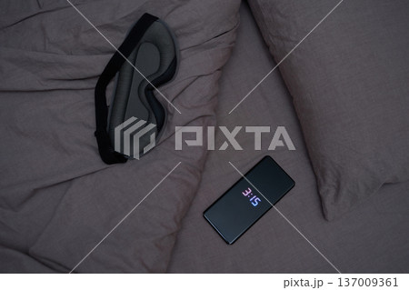Relaxing sleep environment with eye mask and smartphone on soft grey bedding for nighttime routine Relaxing sleep environment with eye mask and smartphone on soft grey bedding for nighttime routine 137009361