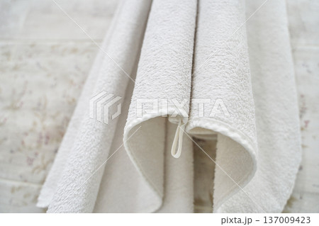 White terry cloth towels hanging neatly in bathroom for home spa relaxation and cleanliness 137009423