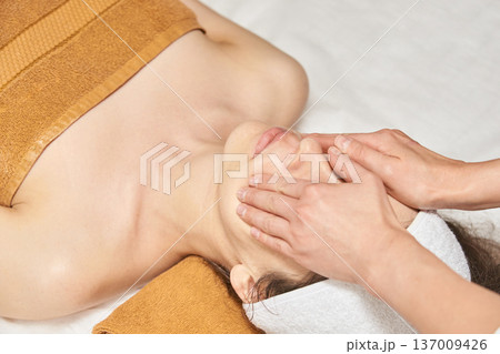 Asian Female Receiving Relaxing Facial Massage At Spa For Rejuvenation And Skincare Treatment Asian Female Receiving Relaxing Facial Massage At Spa For Rejuvenation And Skincare Treatment 137009426