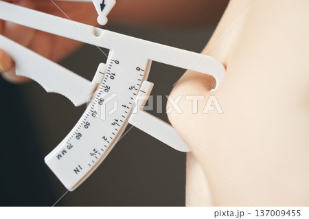 Close-up of caucasian young adult female using body fat caliper for skinfold measurement Close-up of caucasian young adult female using body fat caliper for skinfold measurement 137009455