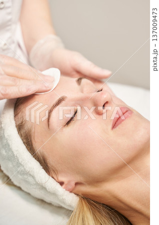 Young caucasian female receiving professional facial treatment at spa with expert care 137009473