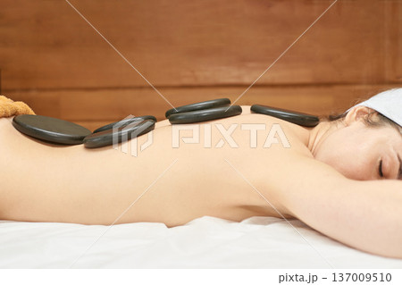 Young Caucasian Female Enjoying Relaxing Hot Stone Massage Therapy At Spa For Stress Relief 137009510