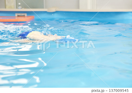 Young caucasian female swimming freestyle in indoor pool demonstrating athletic skills Young caucasian female swimming freestyle in indoor pool demonstrating athletic skills 137009545