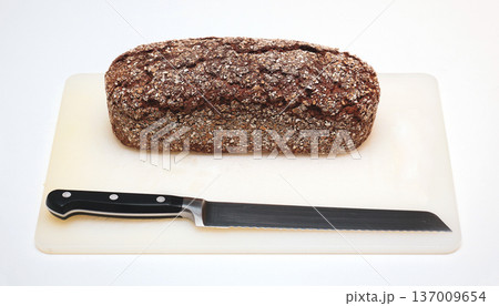 Wholemeal rye bread on chopping board with knife 137009654