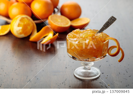 Orange jam in a glass dessert bowl on an old wooden table. Orange jam in a glass dessert bowl on an old wooden table. 137009845