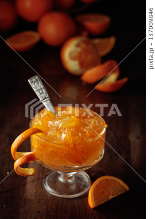 Orange jam in a glass dessert bowl on an old wooden table. 137009846