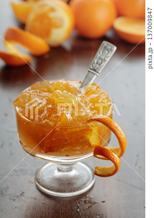 Orange jam in a glass dessert bowl on an old wooden table. Orange jam in a glass dessert bowl on an old wooden table. 137009847