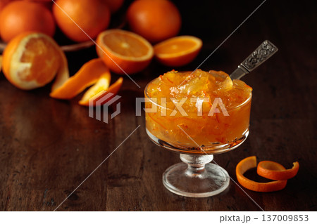 Orange jam in a glass dessert bowl on an old wooden table. 137009853