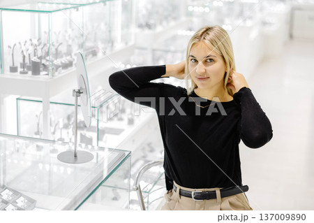 Elegant blonde woman trying a gold necklace in a jewelry shop Elegant blonde woman trying a gold necklace in a jewelry shop 137009890