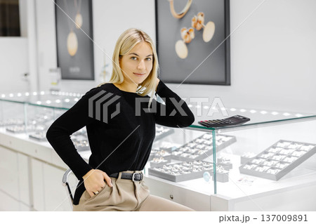 Saleswoman smiling and posing in jewelry shop Saleswoman smiling and posing in jewelry shop 137009891