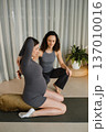 Pregnant woman practicing yoga with instructor in a bright room with curtains and plants during a daytime session focused on prenatal care 137010016