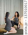 Pregnant woman practicing yoga with instructor in indoor studio in the afternoon while surrounded by soft lighting and calm decor 137010017