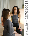 Two women practice yoga together in a bright indoor space with soft lighting in the morning, focusing on connection and support during pregnancy 137010018