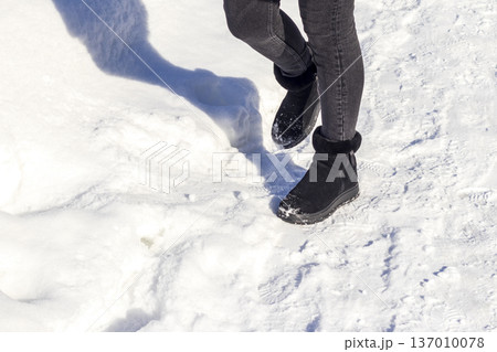 Woman wearing black ankle boots, walking on the snow. Season 137010078