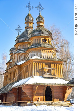 Historic wooden church stands majestically under the bright blue sky in winter wonderland 137010132