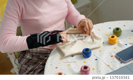Woman practicing therapeutic embroidery with wrist brace Woman practicing therapeutic embroidery with wrist brace 137010381