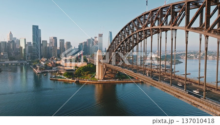 Australia, Sydney: Sydney Harbour Bridge and modern city skyline under sunny morning light, urban infrastructure architecture and road transportation traffic. Drone flight aerial panorama Australia, Sydney: Sydney Harbour Bridge and modern city skyline under sunny morning light, urban infrastructure architecture and road transportation traffic. Drone flight aerial panorama 137010418