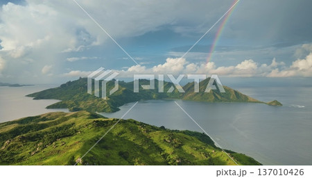 Vibrant rainbow arches Fiji islands with lush green mountains and coastal landscape meeting calm Pacific Ocean under bright sky. Perfect nature background. Travel destination. Aerial view drone flight Vibrant rainbow arches Fiji islands with lush green mountains and coastal landscape meeting calm Pacific Ocean under bright sky. Perfect nature background. Travel destination. Aerial view drone flight 137010426
