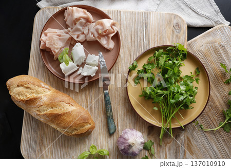 High-quality farm food on wooden cutting board. Top view. Flat lay photo. Soft goat cheese on bread, basil and mortadella sandwich. Italian tradition cuisine. 137010910