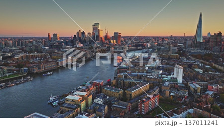 London sunset cityscape aerial perspective, River Thames flowing through modern urban city environment with iconic landmarks - Tower Bridge and The Shard dominating the horizon. Drone flight footage London sunset cityscape aerial perspective, River Thames flowing through modern urban city environment with iconic landmarks - Tower Bridge and The Shard dominating the horizon. Drone flight footage 137011241